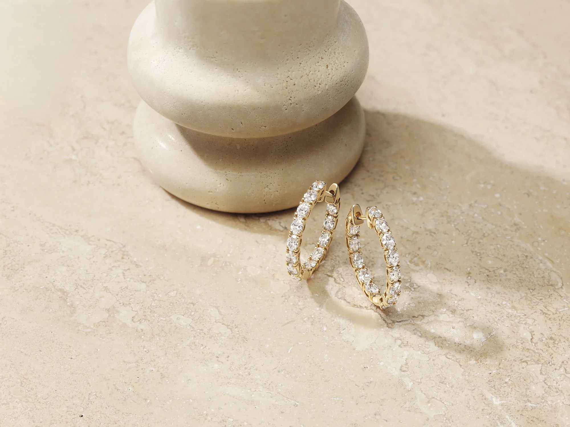 Diamond hoop earrings on a travertine surface