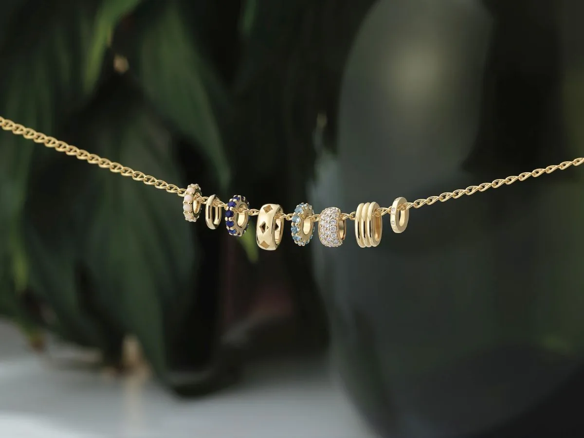 Gold chain with gemstone-set charms in sapphire, blue topaz, and diamond