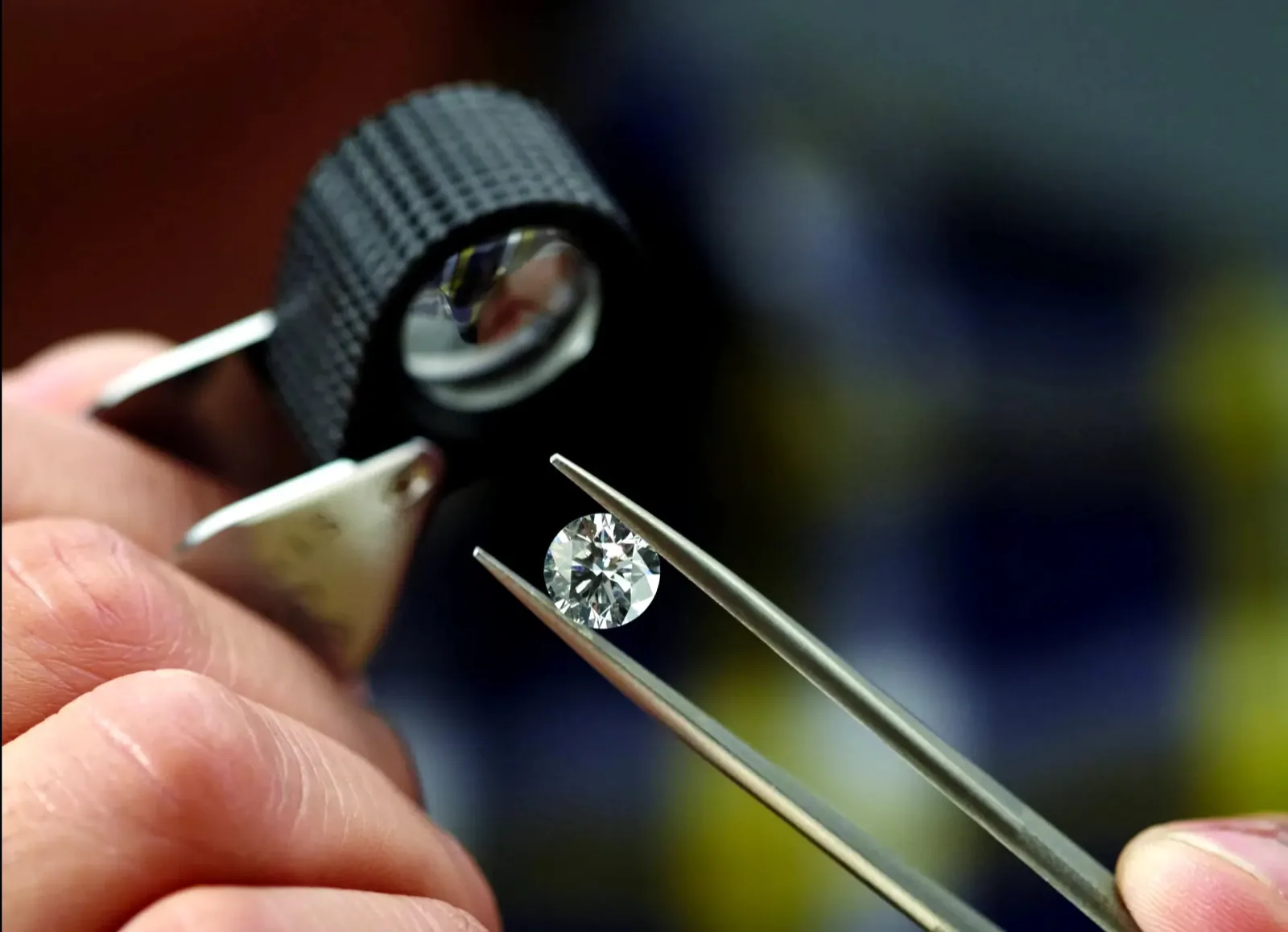 Jeweler examining a diamond with a loupe and tweezers during an appraisal