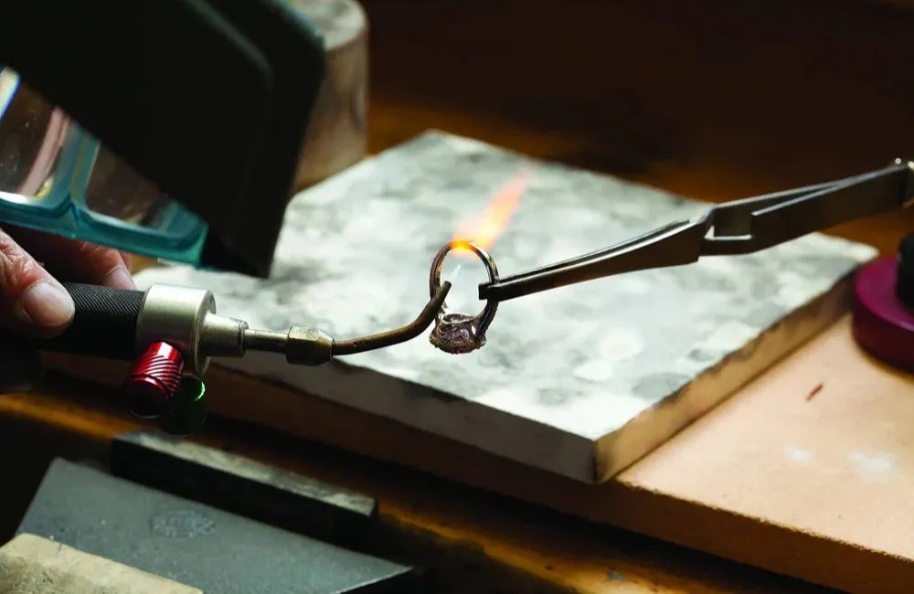 Jeweler torch-soldering a ring at the V Jewelers repair bench in Surprise, AZ