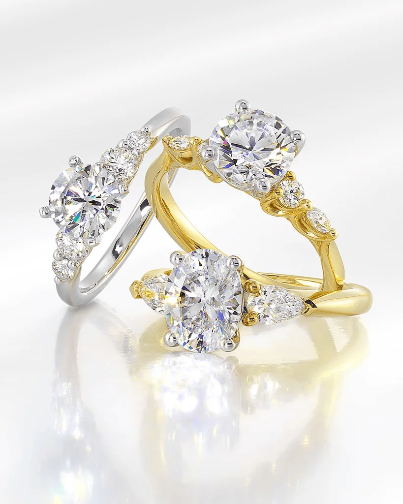 Gold and white gold three-stone engagement rings with oval and round diamonds